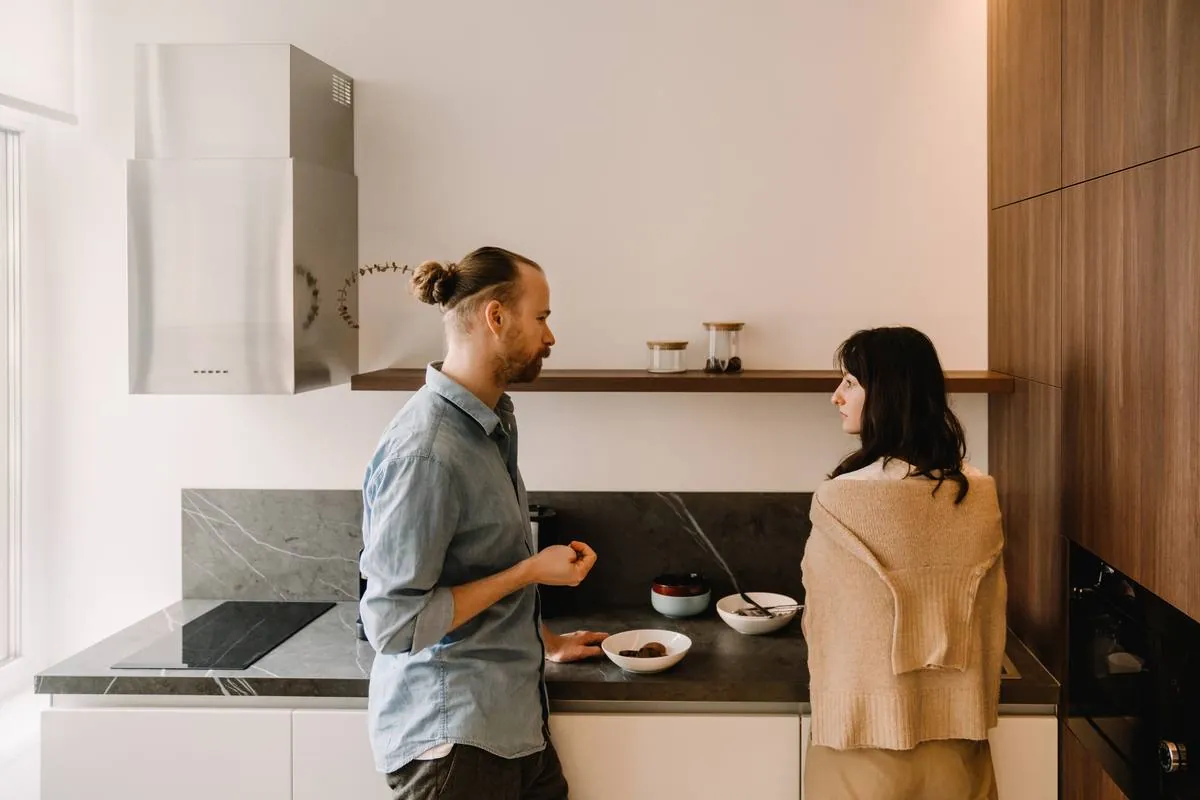 A couple standing at a kitchen counter, turned toward each other
