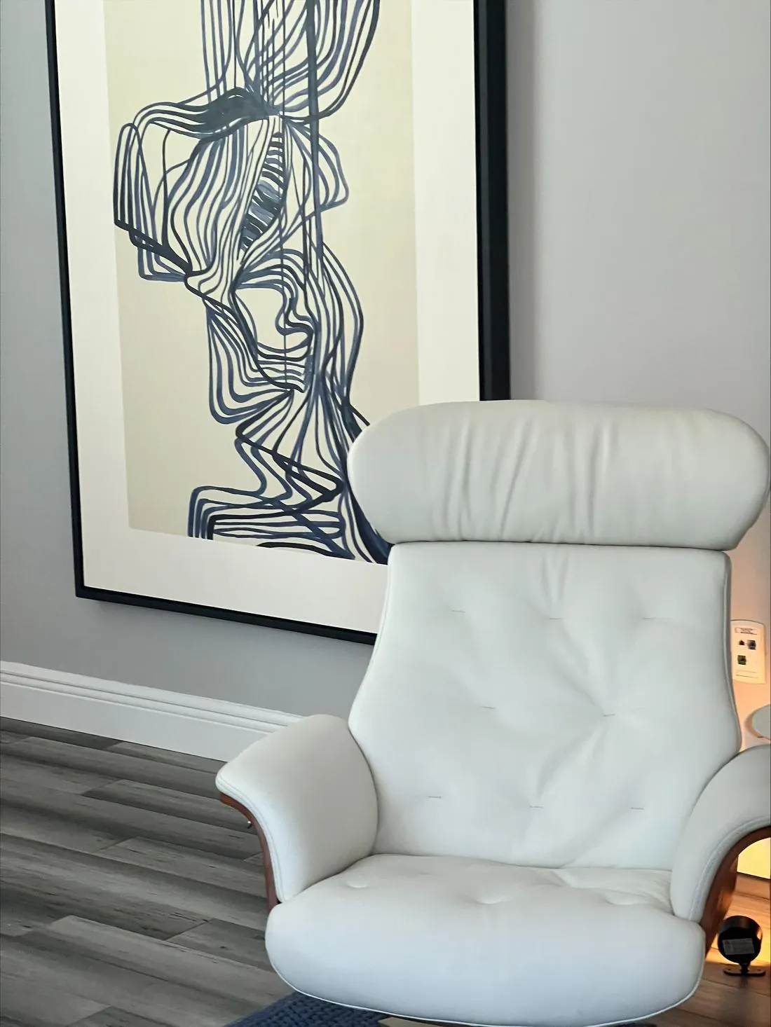 A white leather chair beneath line-drawn artwork in a calm, orderly office